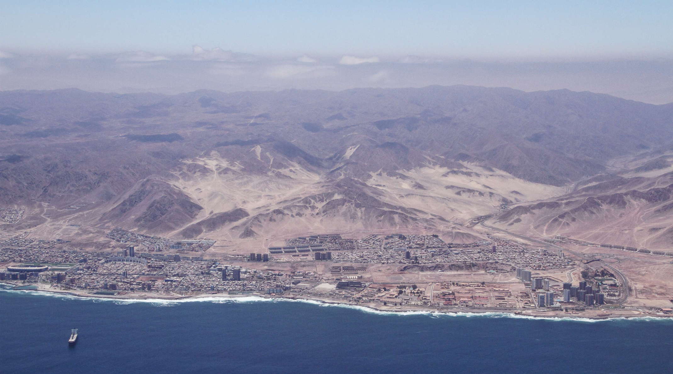 This port city is closely linked to the mining activities in northern Chile. It has been undergoing rapid development in the first decade of the 21st Century and and outperforms most other cities of the country in terms of economic wealth. In 2012, Antofagasta had a population of almost 350,000. The bright lower slopes contrasting to the otherwise dark rocks of the coast range are most likely covered by wind-blown marine sands. WI_ch317b1.jpg