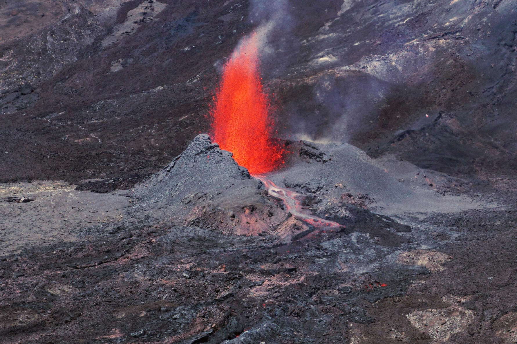 View from the Rempart de Bellecombe between Piton de Partage and Nez Coupé de Sainte-Rose into the Enclos Fouqué. Five days after the start of the initial fissure eruption, the volcanic activity now concentrates at one spot. Material ejected there has piled up to a cone of considerable dimensions. WI_re146a.jpg