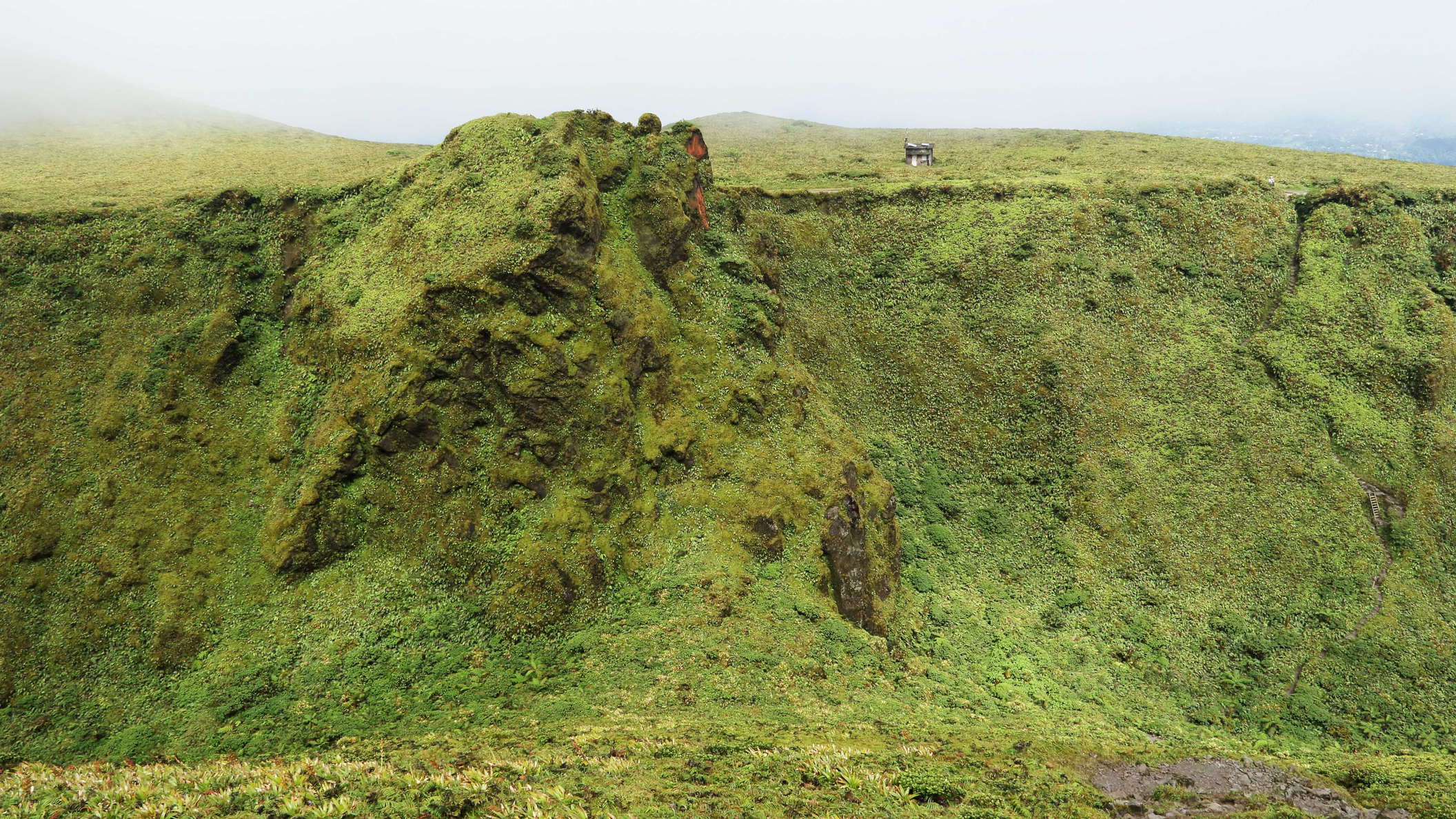 View from the slope of the 1902 lava dome in northeastern direction. The summit of Morne Lacroix (1255) protrudes from the escarpment of the former caldera. Due to the growth of the dome, the base of the escarpment forms a linear depression. The Deuxième Refuge appears right from Morne Lacroix. WI_la739.jpg