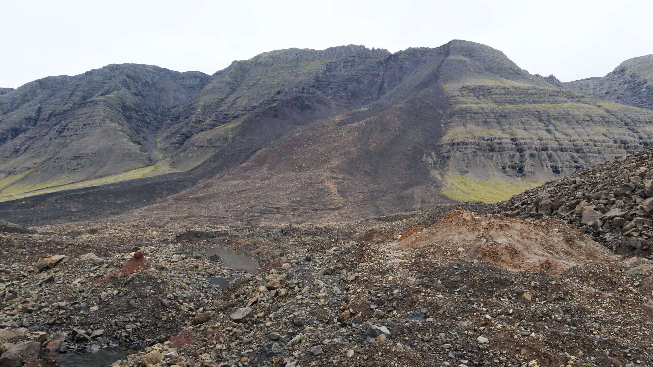 View from the deposit in northwestern direction towards the scarp. This extremely mobile rock avalanche occurred in the morning of 7 July 2018. It travelled over a distance of 2.3 km, increasing its volume from approx. 7 million to more than 10 million cubic metres. Fine sediments within the deposit show that the landslide ploughed the probably water-saturated valley bottom when broadly spreading over flat terrain and blocking the river Hítará. WI_is216.jpg