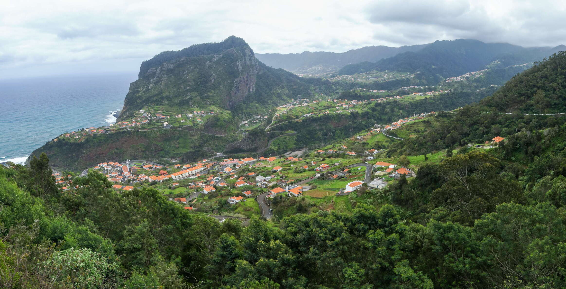 Panoramic view from the road ER 213 in SE direction to the village of Faial (left side) and the cliff of Penha de Águia. This scene illustrates the characteristic land use pattern in this part of the island: the lower slopes represent a mosaic of farmland and settlements, whereas the upper slopes are covered in dense laurel forest (laurisilva). WI_md096.jpg